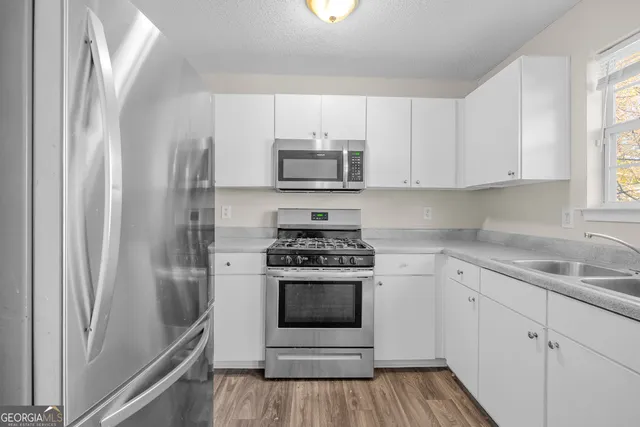 a kitchen with cabinets stainless steel appliances a sink and a window