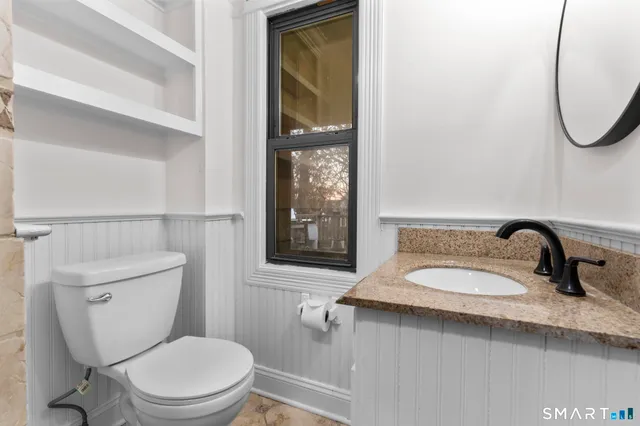 a bathroom with a granite countertop toilet sink and mirror