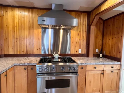 a kitchen with granite countertop wooden cabinets and a stove top oven