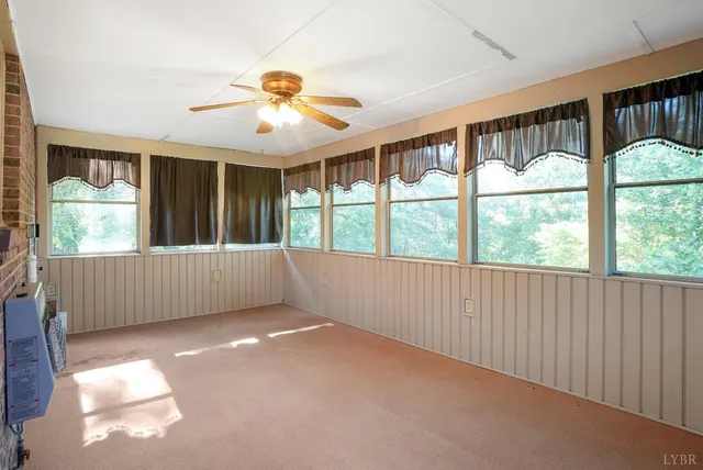 a view of an empty room with window and chandelier fan