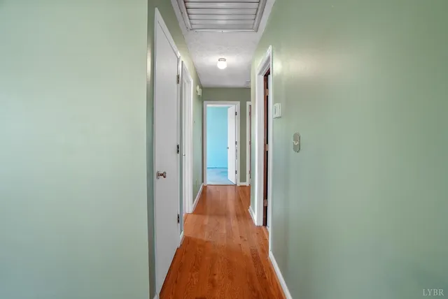 an empty room with windows chandelier fan and hallway