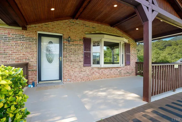 a view of a house with a small yard plants and a large tree