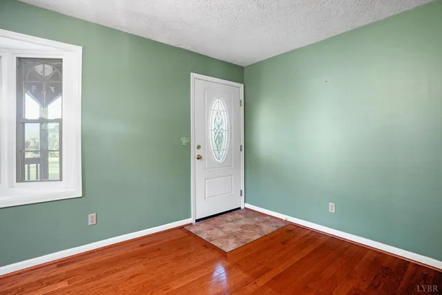 a view of an empty room with window and wooden floor