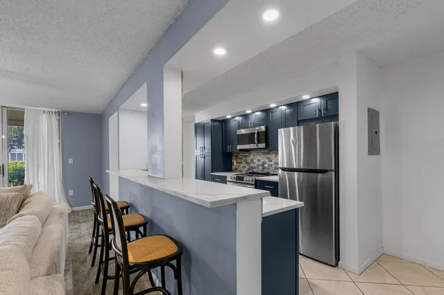 a kitchen with refrigerator and chairs