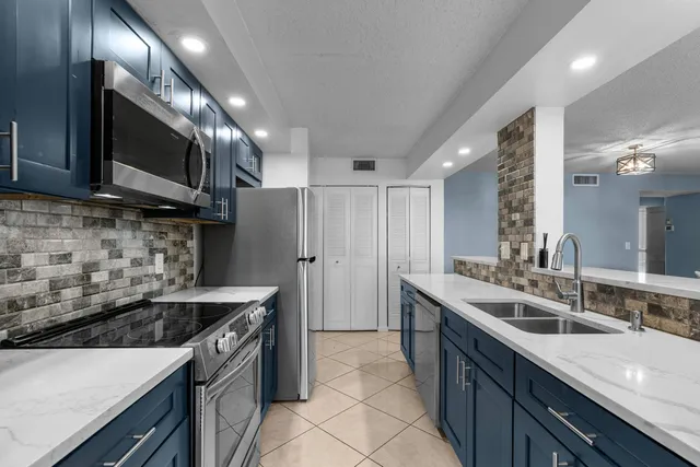 a kitchen with stainless steel appliances granite countertop a sink a stove a microwave a sink and a refrigerator