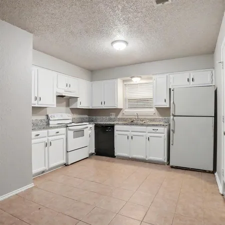 a kitchen with a white stove refrigerator and white cabinets