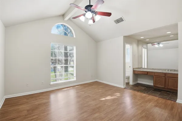 a view of an empty room with a window and kitchen view