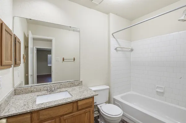 a bathroom with a granite countertop sink toilet mirror and bathtub