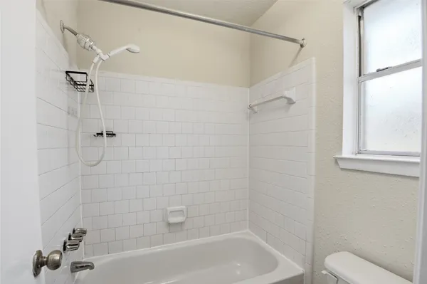 a bathroom with a shower a toilet and a bath tub