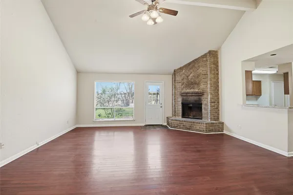an empty room with wooden floor a fireplace and windows