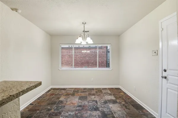 an empty room with chandelier fan and wooden floor
