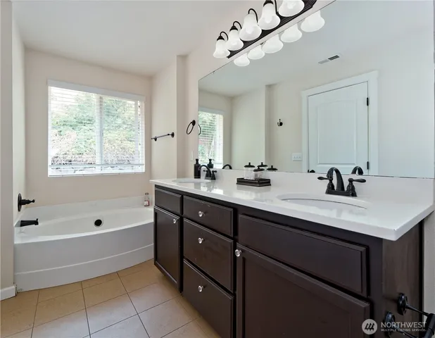 a bathroom with a tub double sink and a mirror