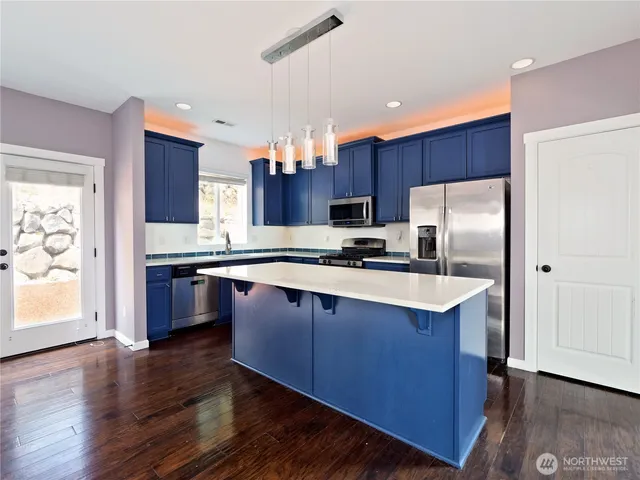 a kitchen with stainless steel appliances wooden floors and wooden cabinets