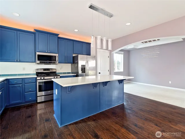 a kitchen with granite countertop wooden floors stainless steel appliances and a window