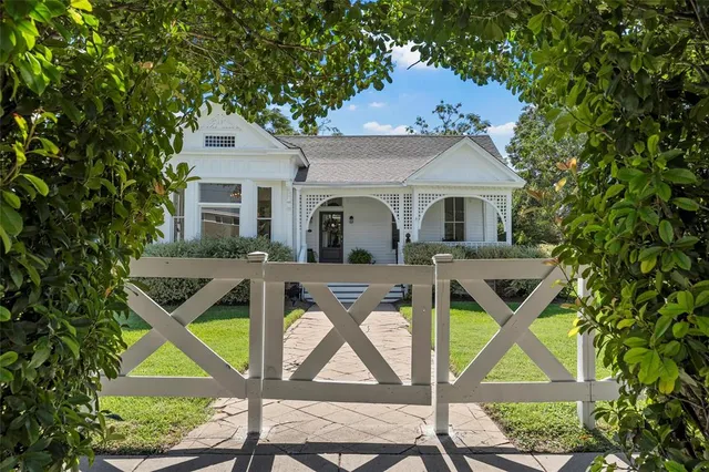 a view of a white house with a big yard and large trees