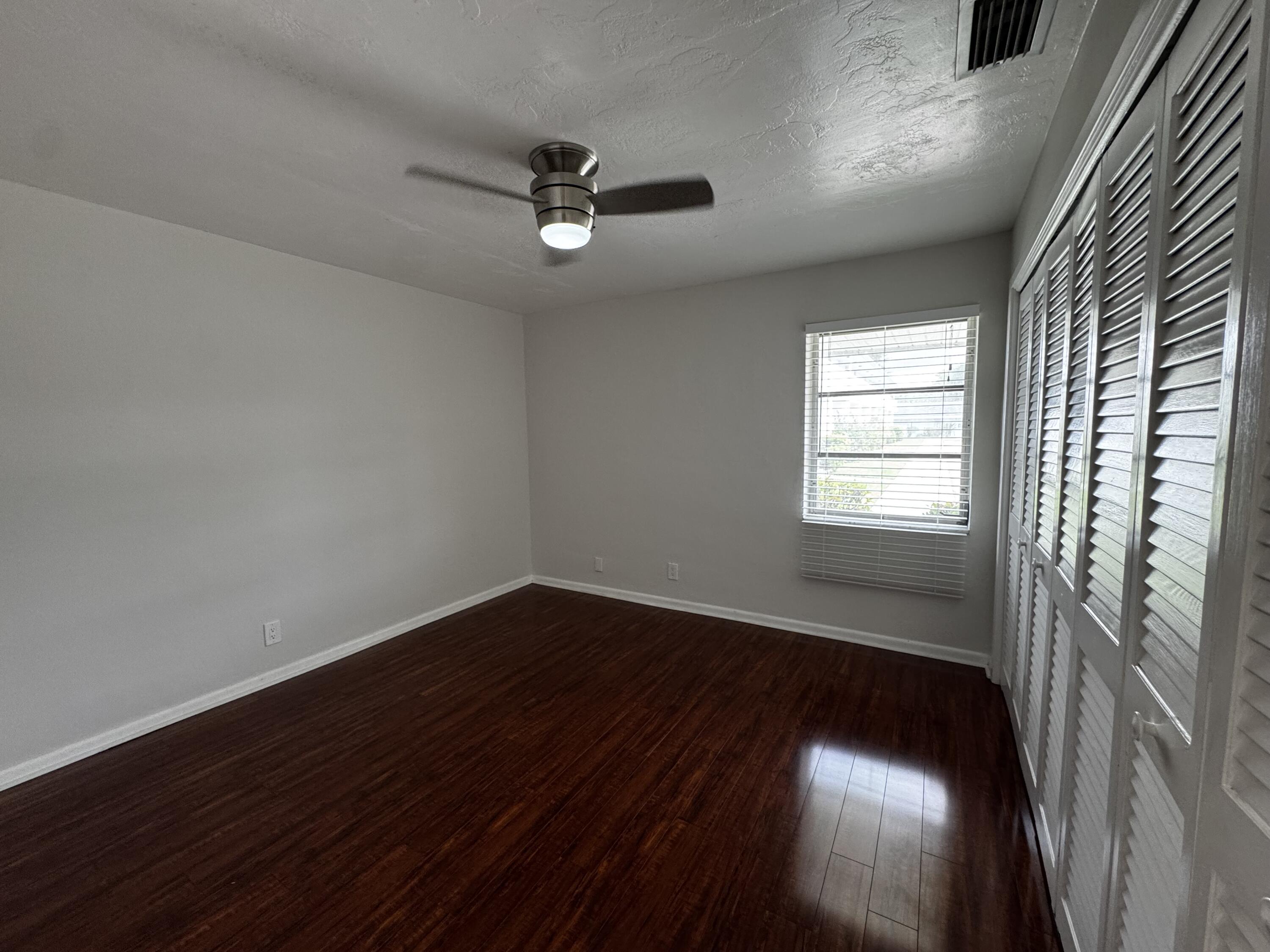 73 East Court, Unit 73 Royal Palm Beach, FL 33411 - Photo 12 of 17 a view of an empty room with wooden floor and a window
