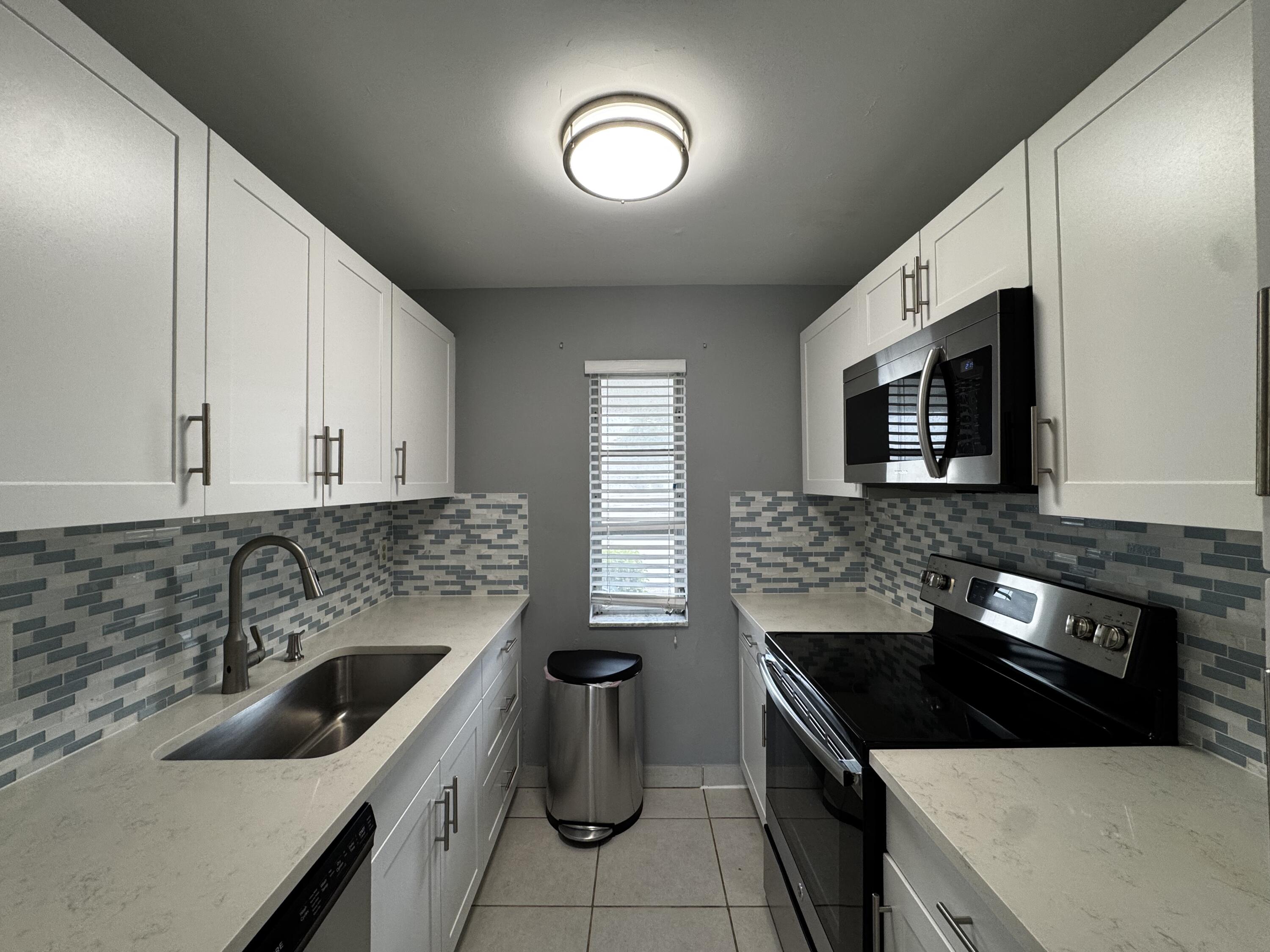 73 East Court, Unit 73 Royal Palm Beach, FL 33411 - Photo 2 of 17 a kitchen with a sink stove and microwave