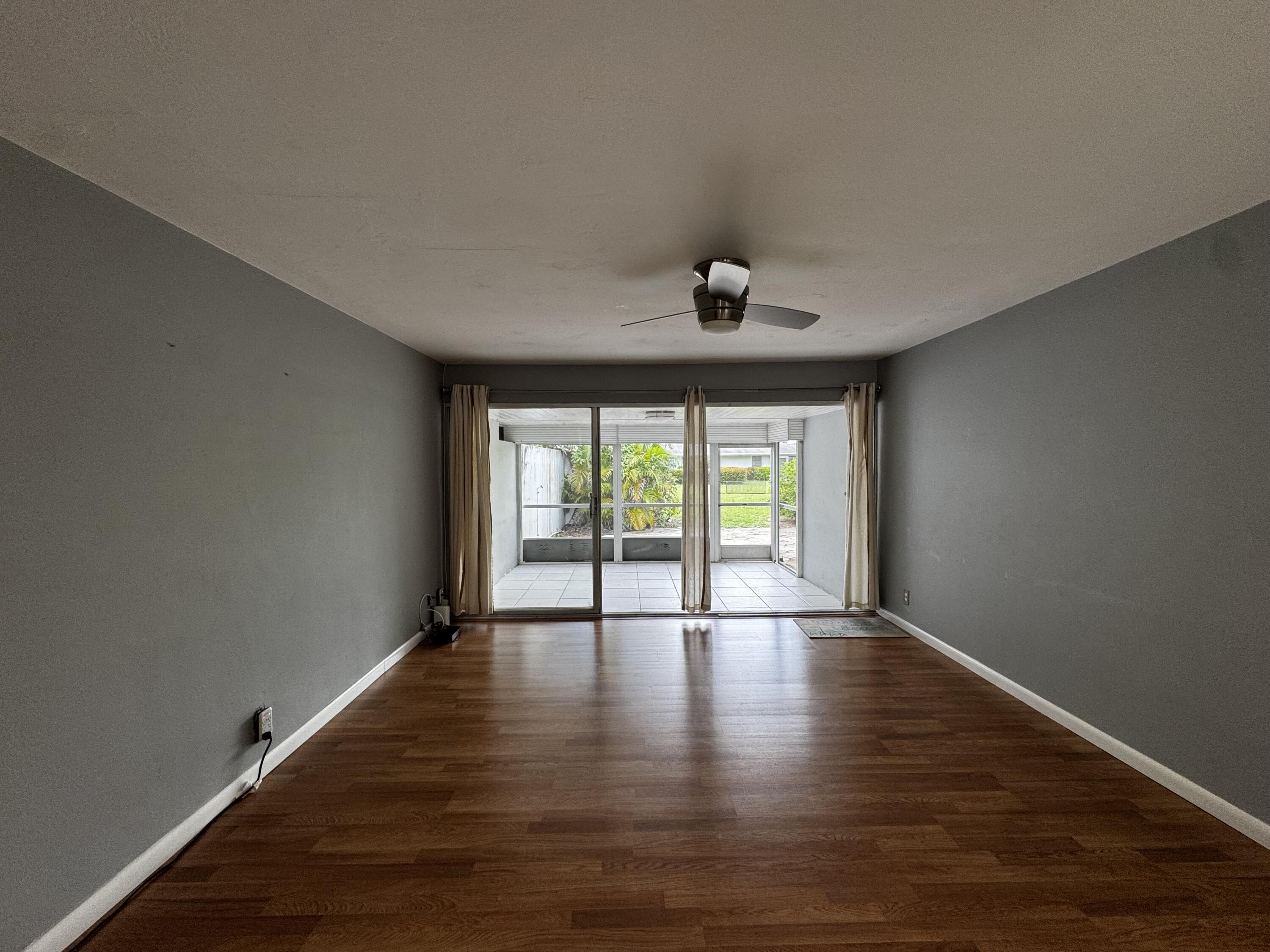 73 East Court, Unit 73 Royal Palm Beach, FL 33411 - Photo 5 of 17 a view of an empty room with wooden floor and a window
