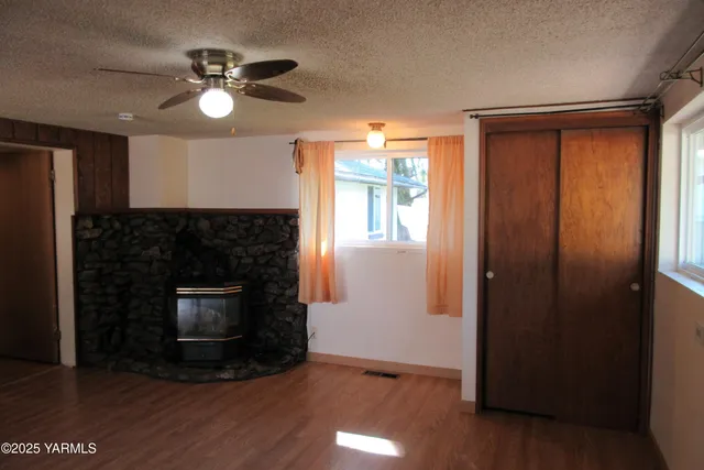 an empty room with wooden floor fireplace and window