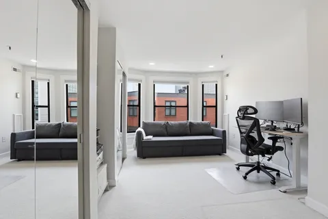 a living room with furniture and a air conditioner vent
