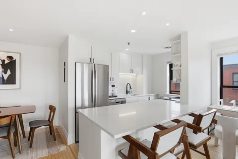 a kitchen with kitchen island a dining table chairs stainless steel appliances and cabinets