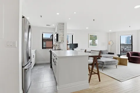 a living room with furniture a wooden floor and a view of kitchen