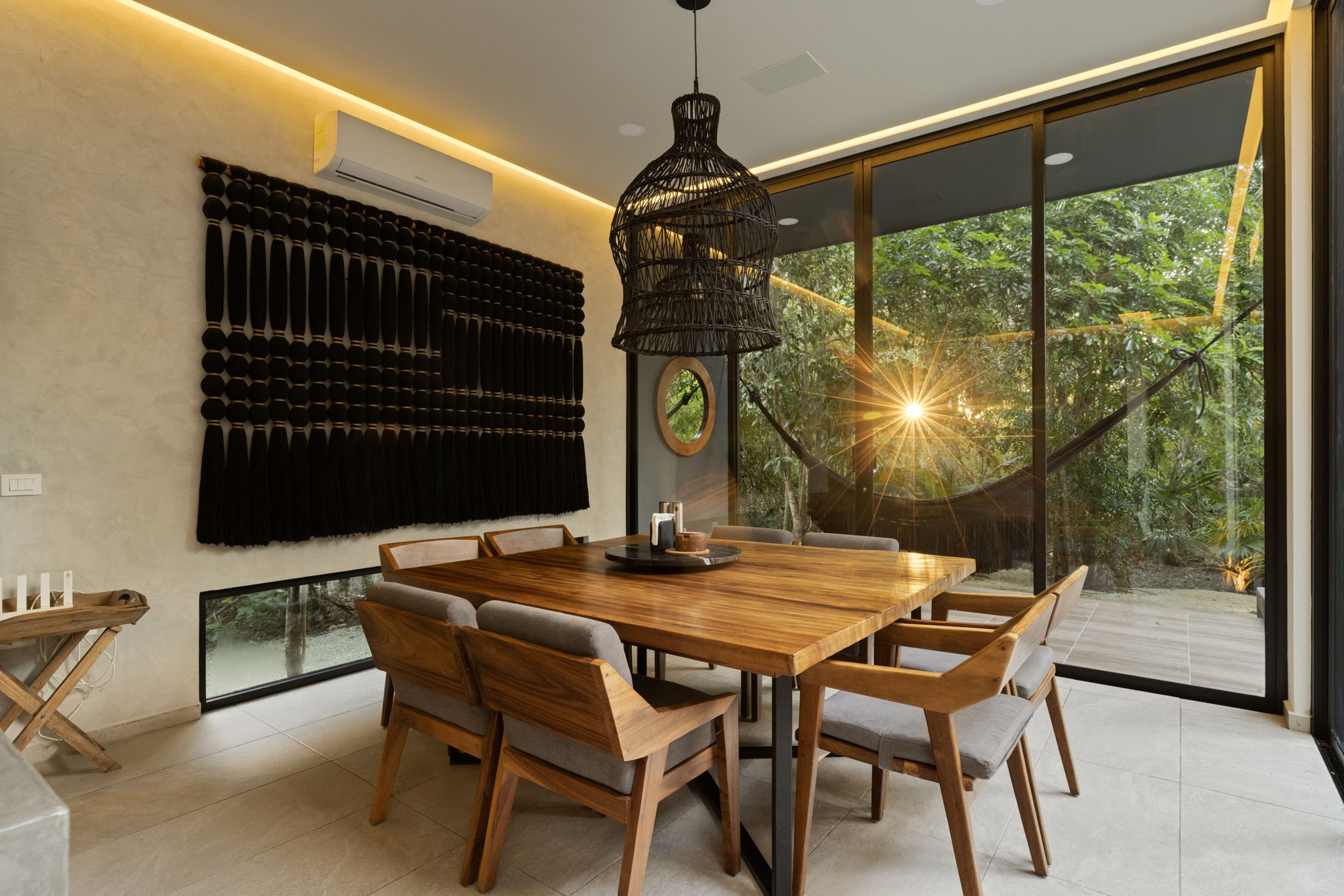 6 Country Club, Unit 4 Nome, TX 77629 - Photo 14 of 45 Floor-to-ceiling glass sliding doors dissolve the barrier between the indoors and nature, bathing the dining room in golden sunset light while offering direct views of the lush jungle canopy.