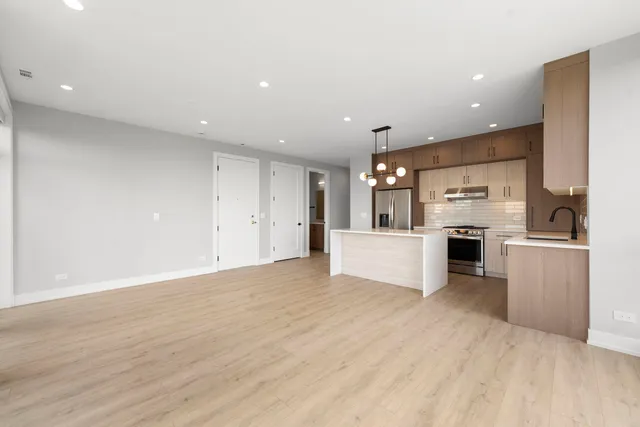 a view of kitchen with kitchen island a sink wooden floor and stainless steel appliances