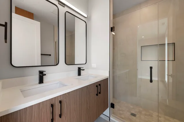 a bathroom with a double vanity sink mirror and shower