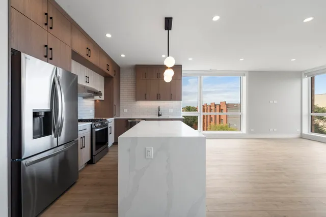 a kitchen with stainless steel appliances granite countertop a refrigerator a oven a sink and a refrigerator