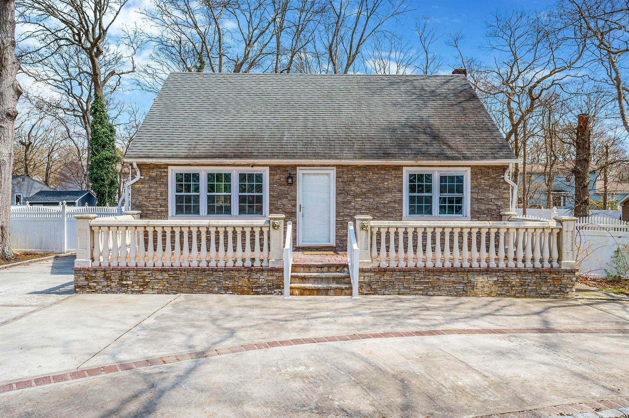 View of front of property featuring a porch, roof with shingles, a chimney, and fence