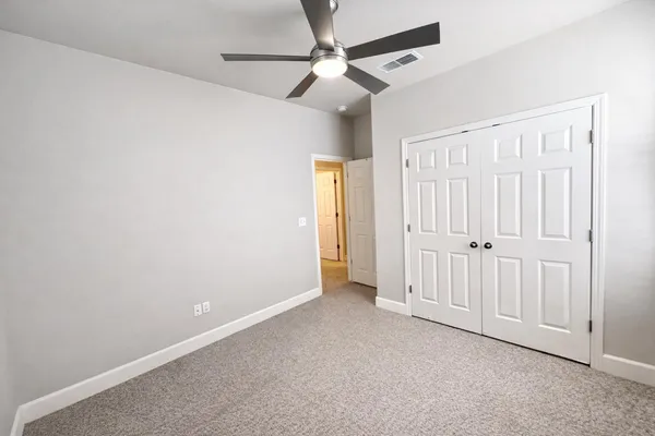 an empty room with windows and fan
