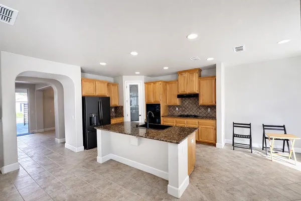 a large kitchen with stainless steel appliances granite countertop a refrigerator and a sink