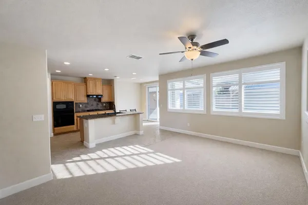 a kitchen with stainless steel appliances kitchen island granite countertop a refrigerator a sink a stove a dining table and chairs