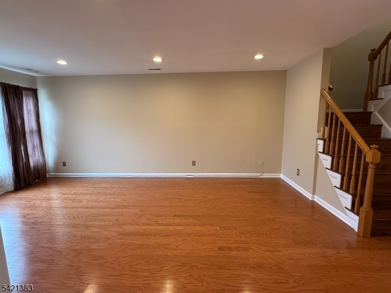 Undisclosed Address Edison, NJ 08820 - Photo 10 of 44 a view of an empty room with wooden floor and stairs