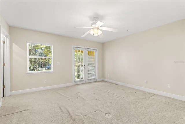 an empty room with chandelier fan and windows