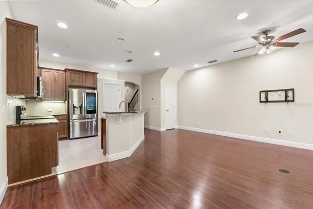 a kitchen with stainless steel appliances granite countertop a refrigerator a sink a stove and white cabinets with wooden floor