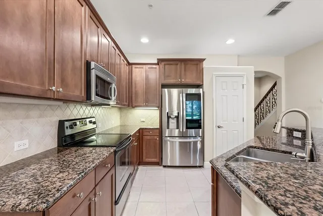 a kitchen with stainless steel appliances granite countertop a sink stove and refrigerator
