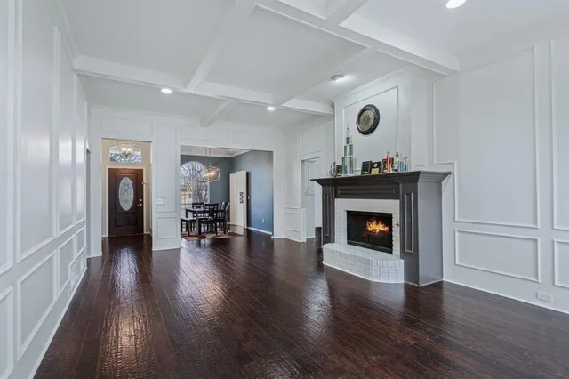 a view of an empty room with wooden floor fireplace and a window