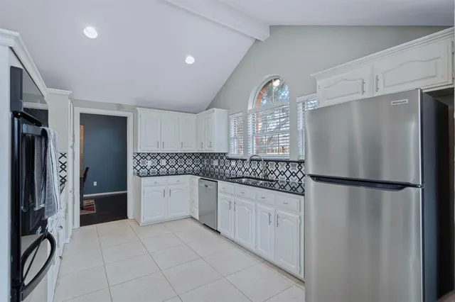 a kitchen with white cabinets and refrigerator