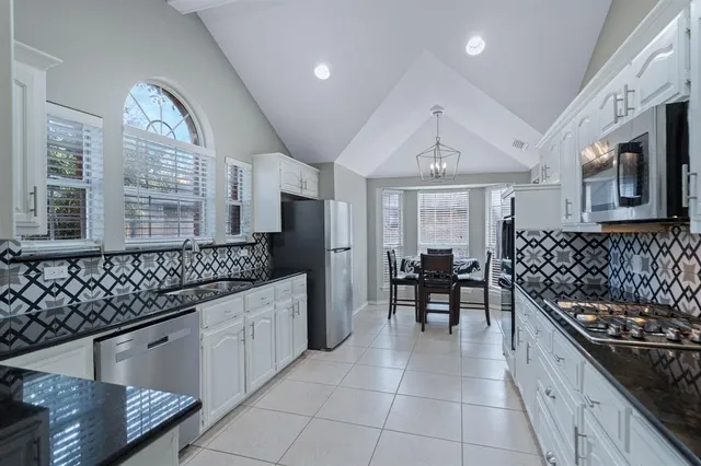 a kitchen with stainless steel appliances granite countertop a stove a sink and a refrigerator