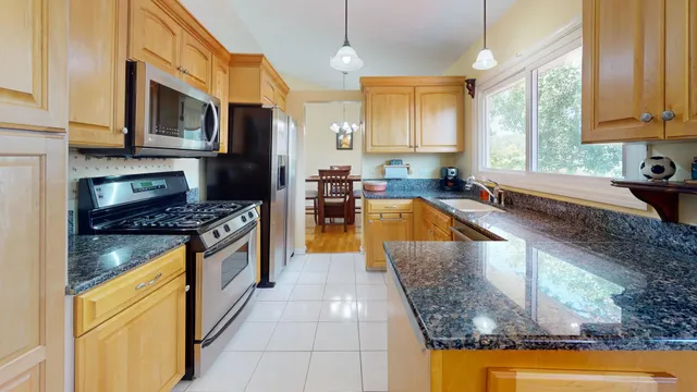 a kitchen with stainless steel appliances granite countertop a stove a sink and a microwave