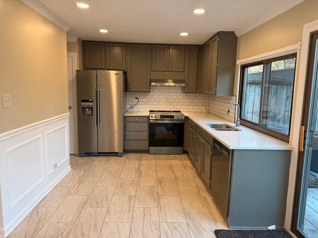 a kitchen with stainless steel appliances granite countertop a refrigerator a sink and a stove