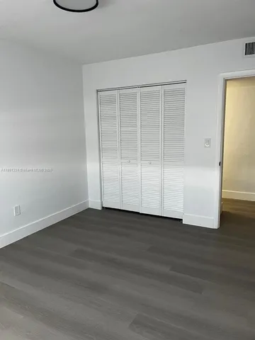 a view of an empty room with wooden floor and closet