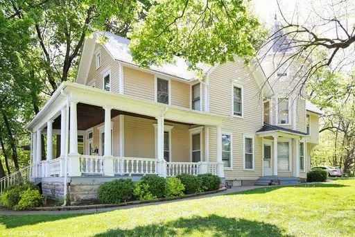 a view of a white house with a large windows and a big yard and large trees