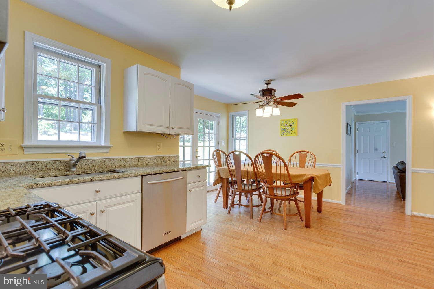1524 Laurel Hill Road Vienna, VA 22182 - Photo 3 of 29 a kitchen with granite countertop a stove a sink dishwasher a dining table and chairs with wooden floor