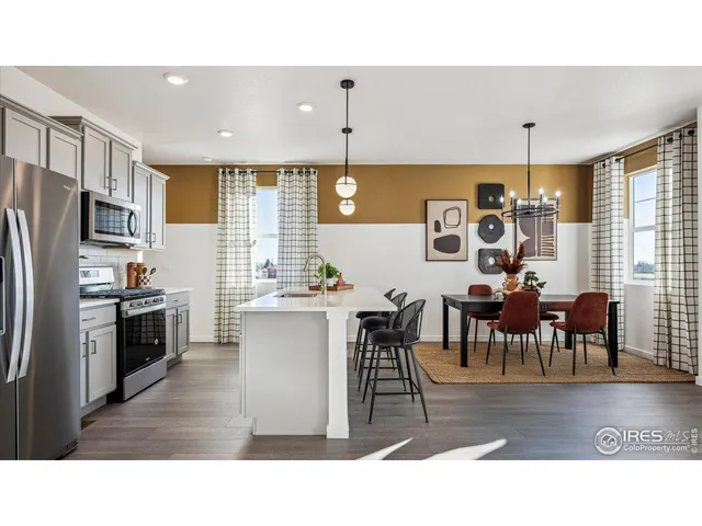 a kitchen with stainless steel appliances kitchen island granite countertop a table chairs and a refrigerator