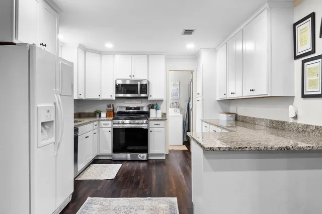 a kitchen with stainless steel appliances granite countertop a refrigerator a stove a sink and white cabinets