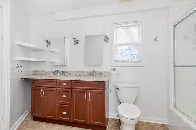 a bathroom with a granite countertop toilet sink and mirror
