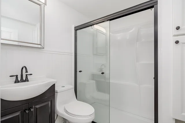 a bathroom with a shower sink vanity and toilet